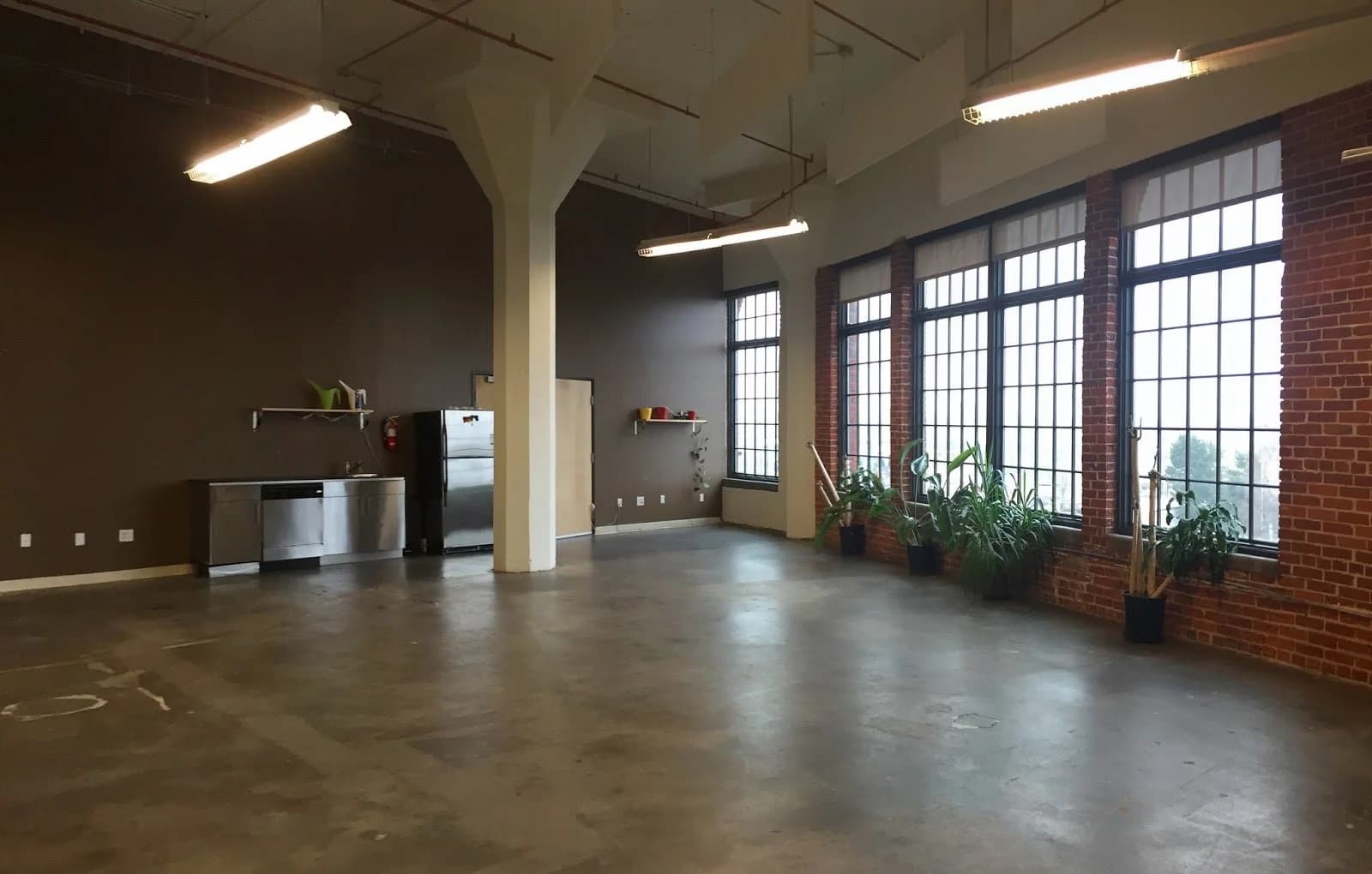 Open commercial loft with polished concrete floor, brick piers and tall industrial windows