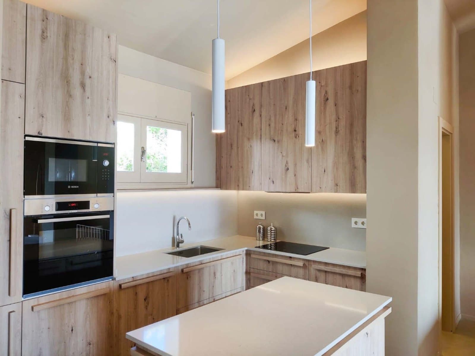 Microcement kitchen with pale oak cabinetry and a seamless white worktop
