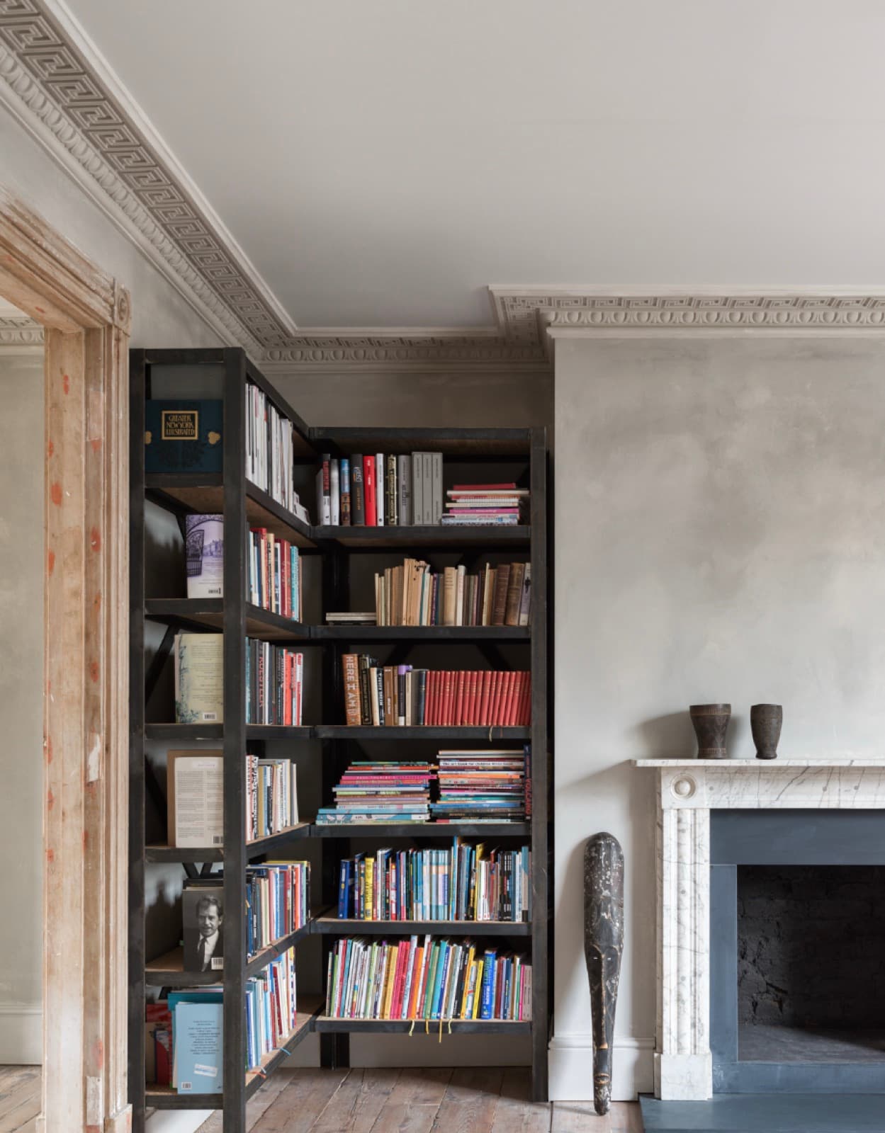 Aged, softly mottled plaster wall beside a marble fireplace and built-in bookshelf